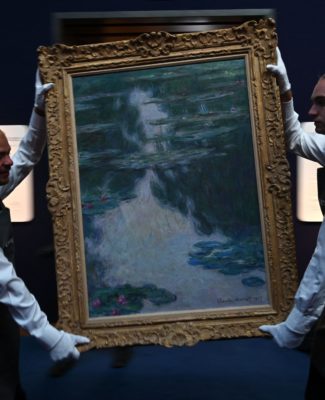 Gallery assistants hold an artwork entitled Nymphéas, temps gris (Water Lilies, Grey Weather) by French painter Claude Monet during a photocall for 20th/21st Century: London to Paris Sale Series at Christie's auction house in London on June 22, 2022. - The artwork was estimated to be sold for GBP 20-30 million (EUR 23.2-35 million, USD 24.4-36.7 million). (Photo by JUSTIN TALLIS/AFP via Getty Images)