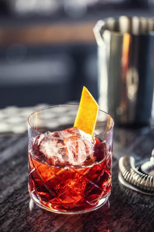 Aperitif in a cocktail glass with ice cube and lemon garnish