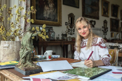 English wallpaper designer Mia Reay sitting at her desk