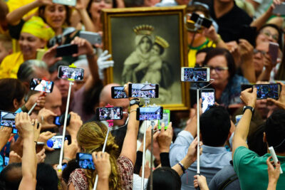 People holding selfie sticks and mobile phones, take photos of Pope Francis as he arrives for his weekly general audience in Paul VI hall at The Vatican, 2018.